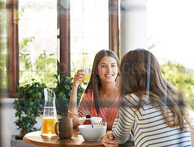 Buy stock photo Shot of two friends eating breakfast together on a balcony