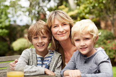 Buy stock photo Portrait of a grandmother hugging her grandsons while sitting at a table in her yard