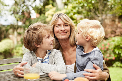 Buy stock photo Portrait of a grandmother hugging her grandsons while sitting at a table in her yard
