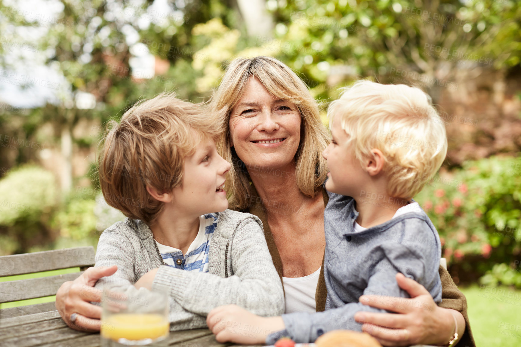 Buy stock photo Outdoor, lunch and grandma with children, smile and bonding with mature woman on weekend or together. Portrait, happy person and hug with kids in backyard, family and relax with grandparent at house