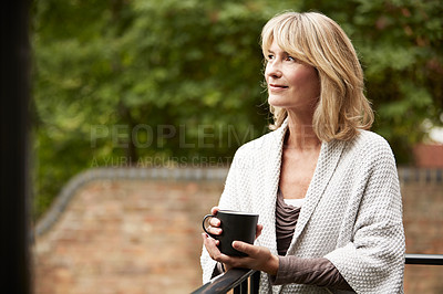 Buy stock photo Shot of a mature woman standing outside her home drinking coffee