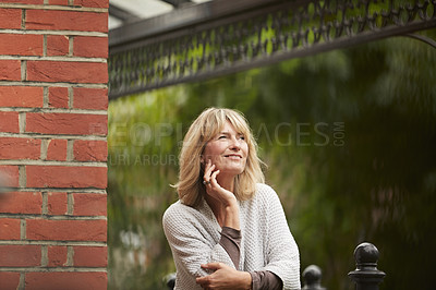 Buy stock photo Shot of a mature woman leaning against the railing of her front porch