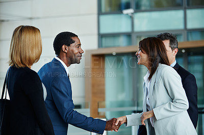 Buy stock photo Shot of businesspeople shaking hands in the lobby of an office building