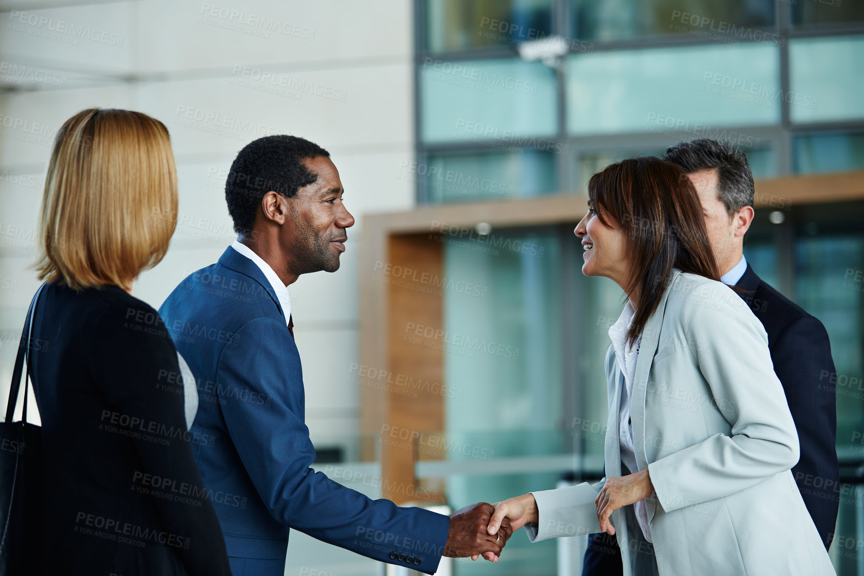 Buy stock photo Shot of businesspeople shaking hands in the lobby of an office building