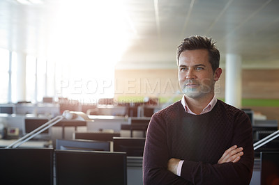 Buy stock photo Shot of a businessman standing with his arms folded in his office