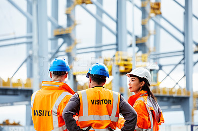 Buy stock photo Rearview shot of three workers talking while standing on a commercial dock