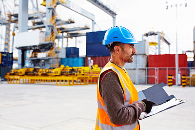 Buy stock photo Shot of man reading paperwork while standing on a large commercial dock