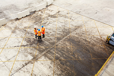Buy stock photo High angle shot of three workers talking together while standing on a commercial dock