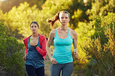 Buy stock photo Shot of two young woman out for a cross country run