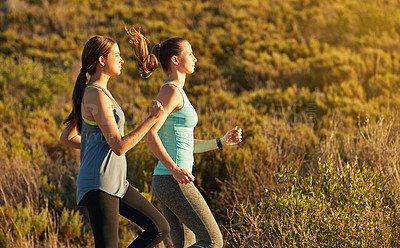 Buy stock photo Shot of two young woman out for a cross country run
