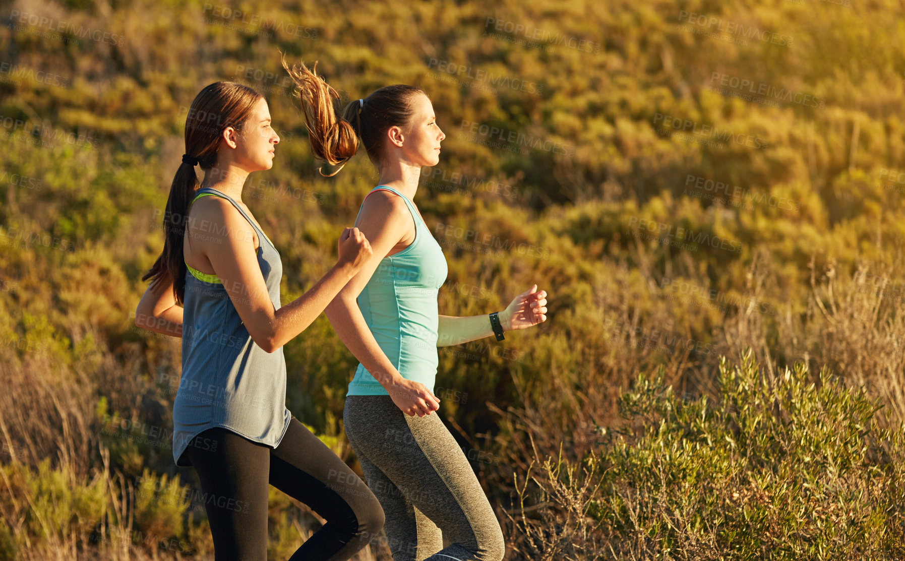 Buy stock photo Shot of two young woman out for a cross country run