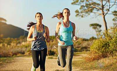 Buy stock photo Shot of two young woman out for a cross country run