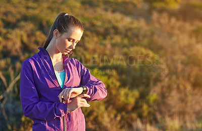 Buy stock photo Shot of a young woman checking her time while out for a trail run