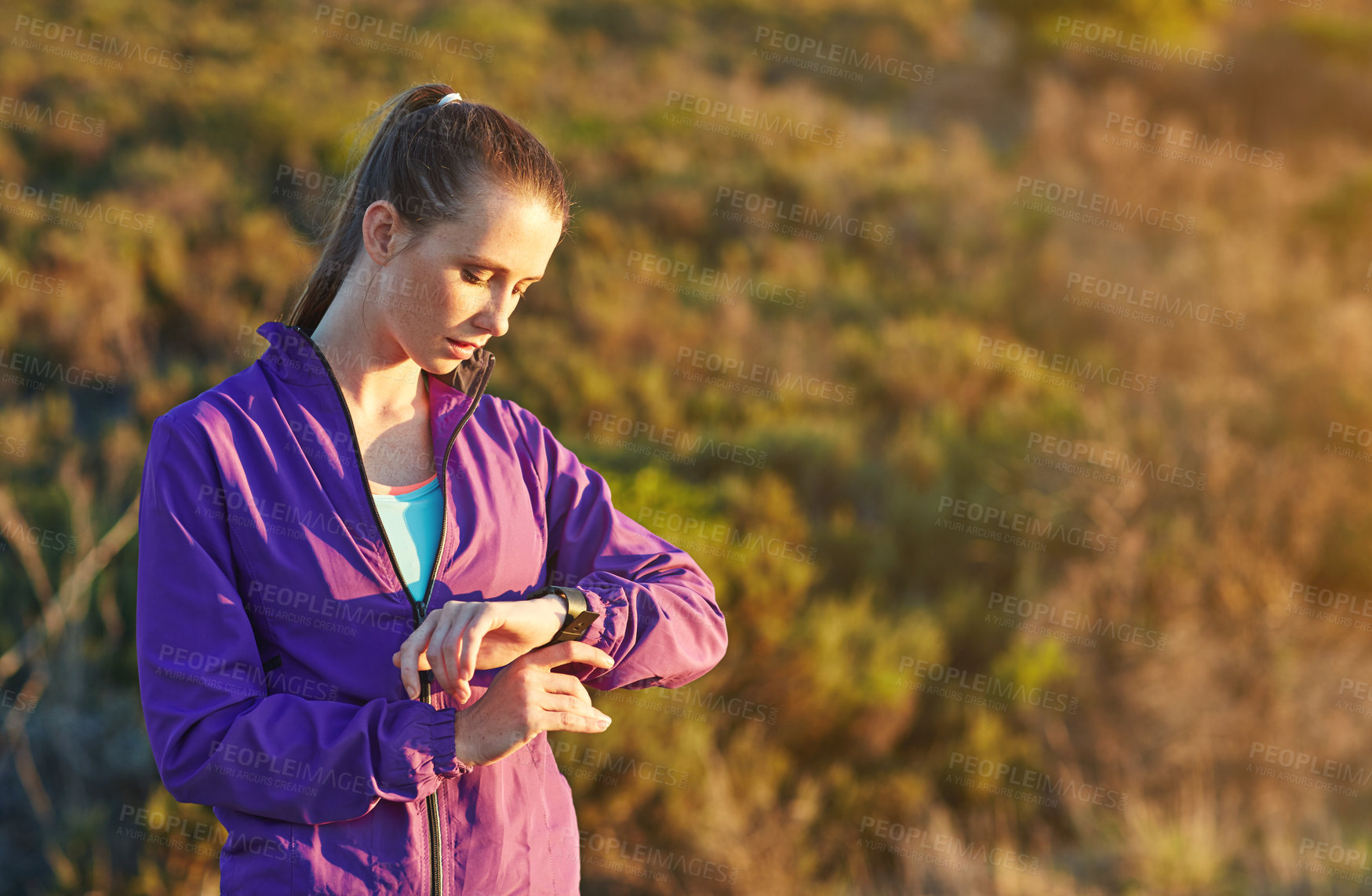 Buy stock photo Shot of a young woman checking her time while out for a trail run