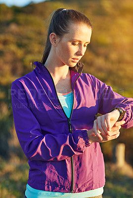 Buy stock photo Shot of a young woman checking her time while out for a trail run