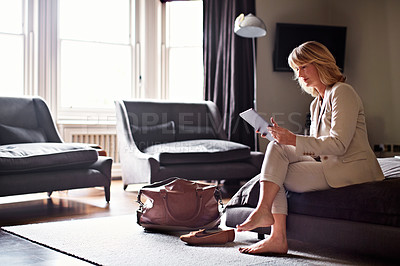 Buy stock photo Shot of a mature businesswoman sitting on a hotel bed using a digital tablet