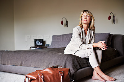 Buy stock photo Shot of a mature businesswoman sitting on hotel bed with her bags