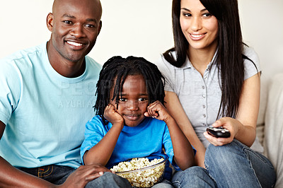 Buy stock photo Cropped shot of a young family of three watching a movie