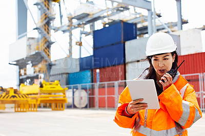 Buy stock photo Shot of a woman in workwear talking on a walkie talkie while standing on a commercial dock