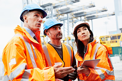 Buy stock photo Shot of three workers talking together over a digital tablet while standing on a commercial dock
