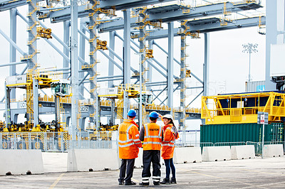 Buy stock photo Shot of three workers talking together while standing on a commercial dock