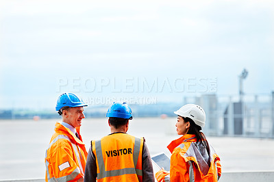 Buy stock photo Shot of three workers talking together while standing on a commercial dock