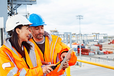 Buy stock photo Shot of two workers talking together over a digital tablet while standing on a commercial dock