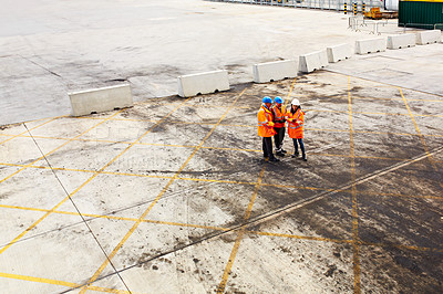 Buy stock photo High angle shot of three workers talking together while standing on a commercial dock
