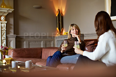 Buy stock photo Shot of a woman drinking wine while talking with her daughter on the living room sofa