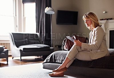 Buy stock photo Shot of a mature businesswoman using her tablet while sitting on her hotel bed