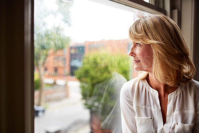 Buy stock photo Cropped shot of a mature woman looking out of her living room window