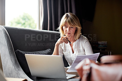 Buy stock photo Shot of a mature businesswoman going over some paperwork while sitting on her hotel bed