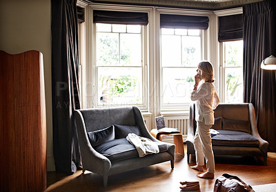 Buy stock photo Full length shot of a mature woman talking on her cellphone while standing in the living room