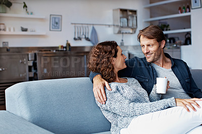 Buy stock photo Shot of a content mature couple sitting on their living room sofa drinking coffee