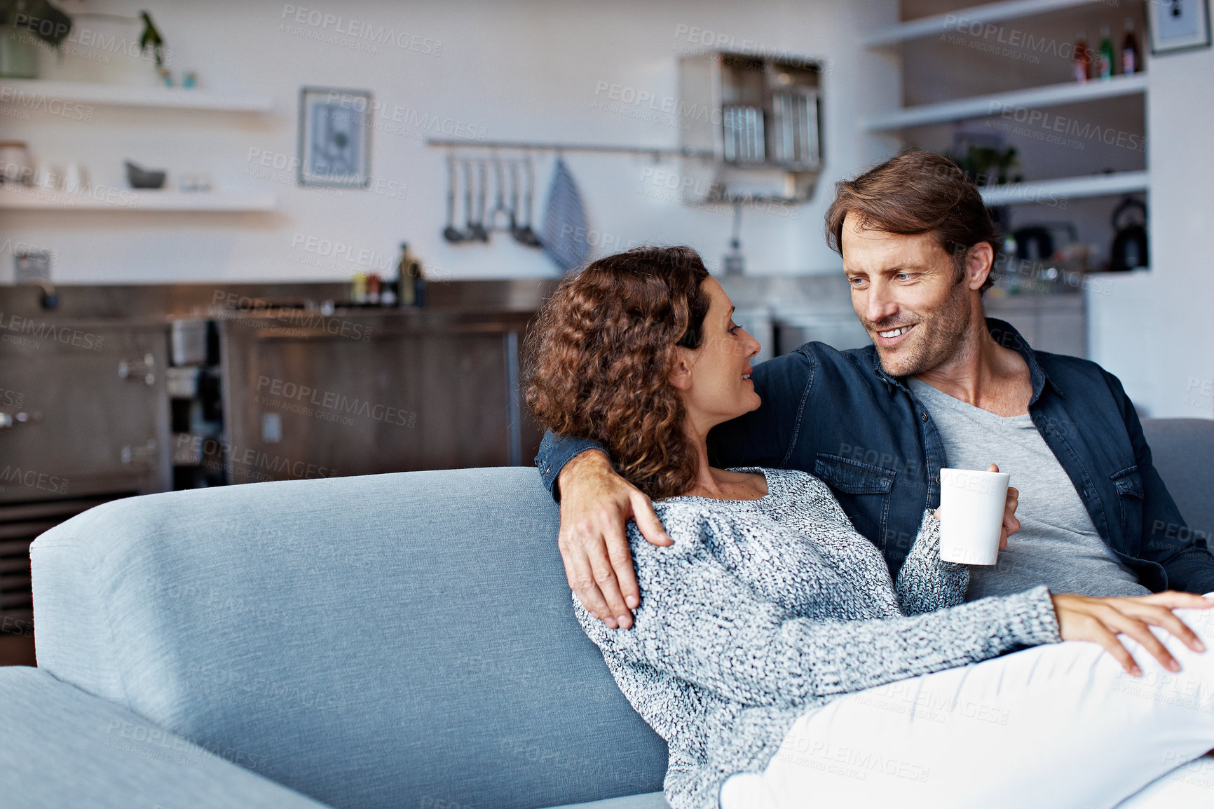 Buy stock photo Shot of a content mature couple sitting on their living room sofa drinking coffee