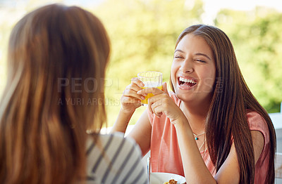 Buy stock photo Shot of two friends eating breakfast together on a balcony