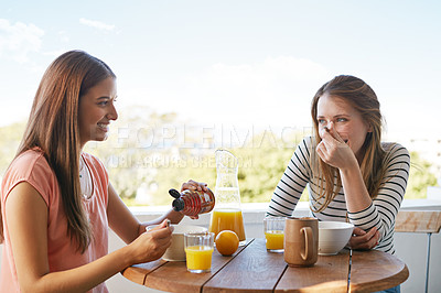 Buy stock photo Shot of two friends eating breakfast together on a balcony