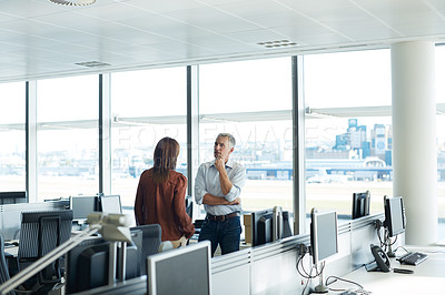 Buy stock photo Shot of two coworkers talking together while standing in an office