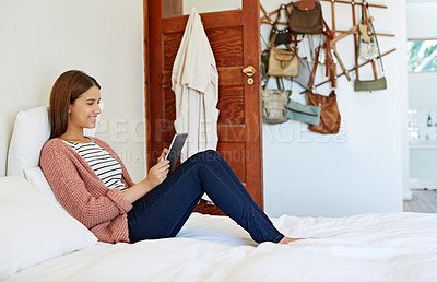 Buy stock photo Portrait of a young woman sitting on her bed using a digital tablet