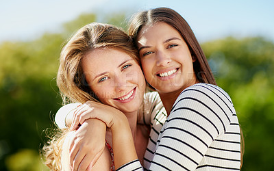 Buy stock photo Portrait of two young friends hugging while enjoying a day outside together