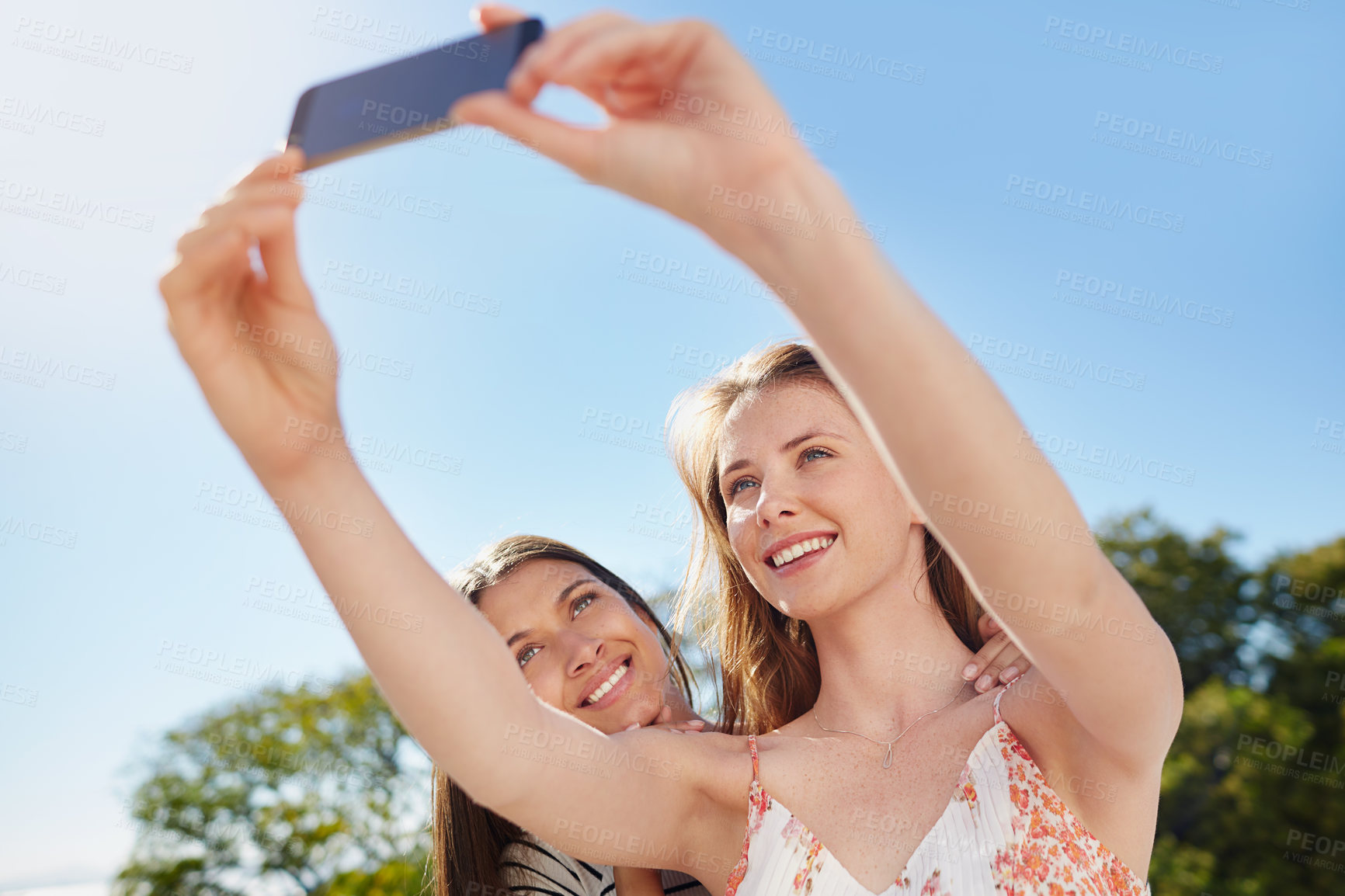 Buy stock photo Shot of two friends taking a selfie together while standing outside