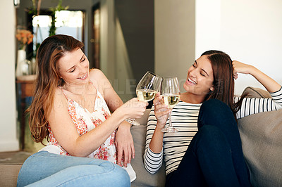 Buy stock photo Shot of two friends talking together and drinking wine while sitting on the sofa at home