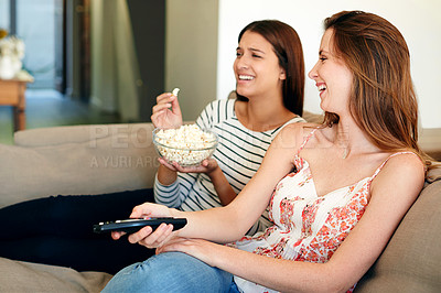 Buy stock photo Shot of two friends watching a movie together on the sofa at home
