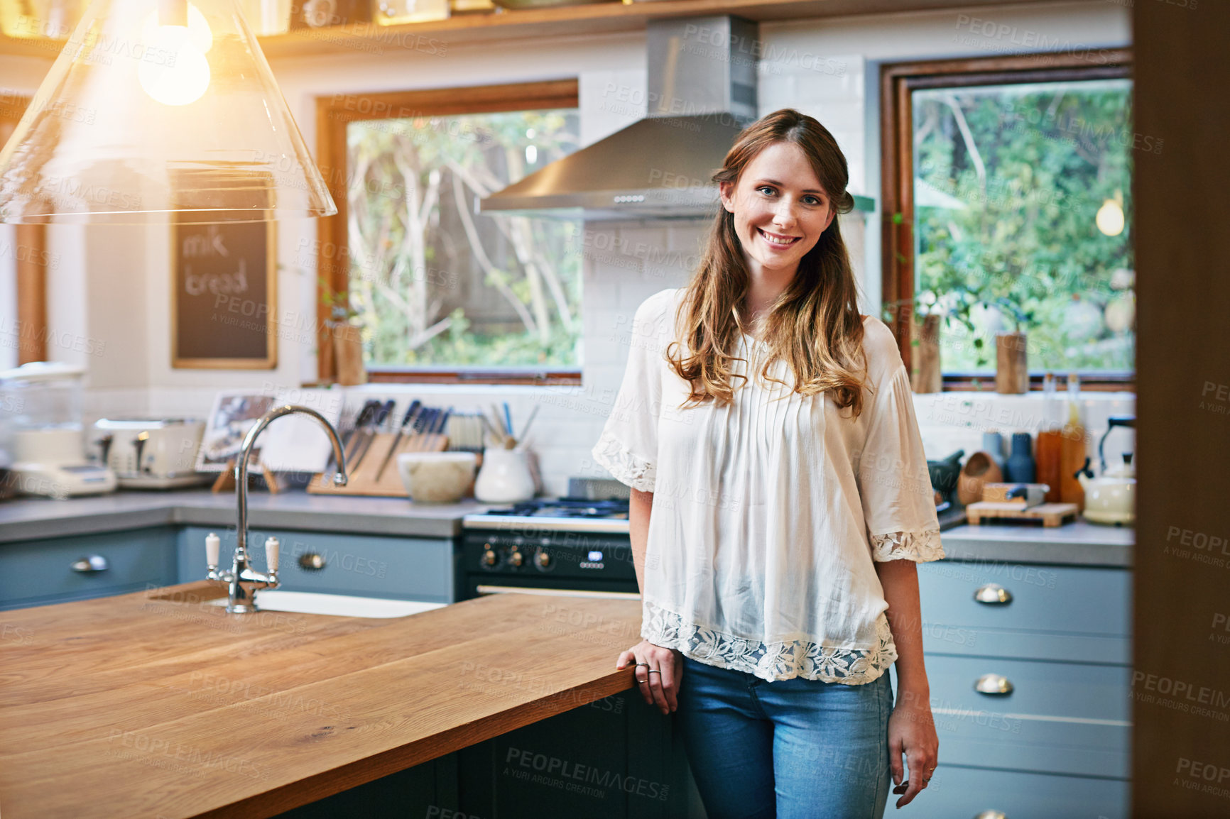 Buy stock photo Portrait of a smiling young woman standing in a kitchen