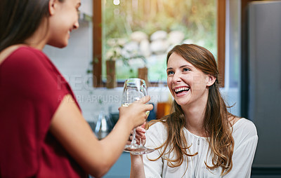 Buy stock photo Shot of two friends hanging out in a kitchen drinking wine together