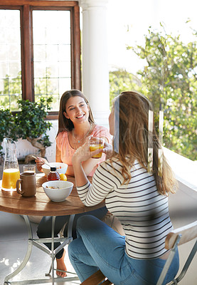 Buy stock photo Shot of two friends eating breakfast together on a balcony
