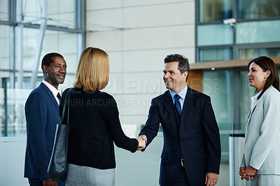 Buy stock photo Shot of businesspeople shaking hands in the lobby of an office building