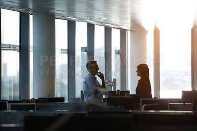 Buy stock photo Shot of two businesspeople talking together in the office late in the afternoon