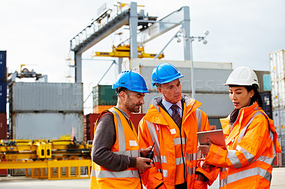 Buy stock photo Shot of three workers talking together over a digital tablet while standing on a commercial dock