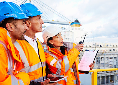 Buy stock photo Shot of three workers talking together while working on a commercial dock